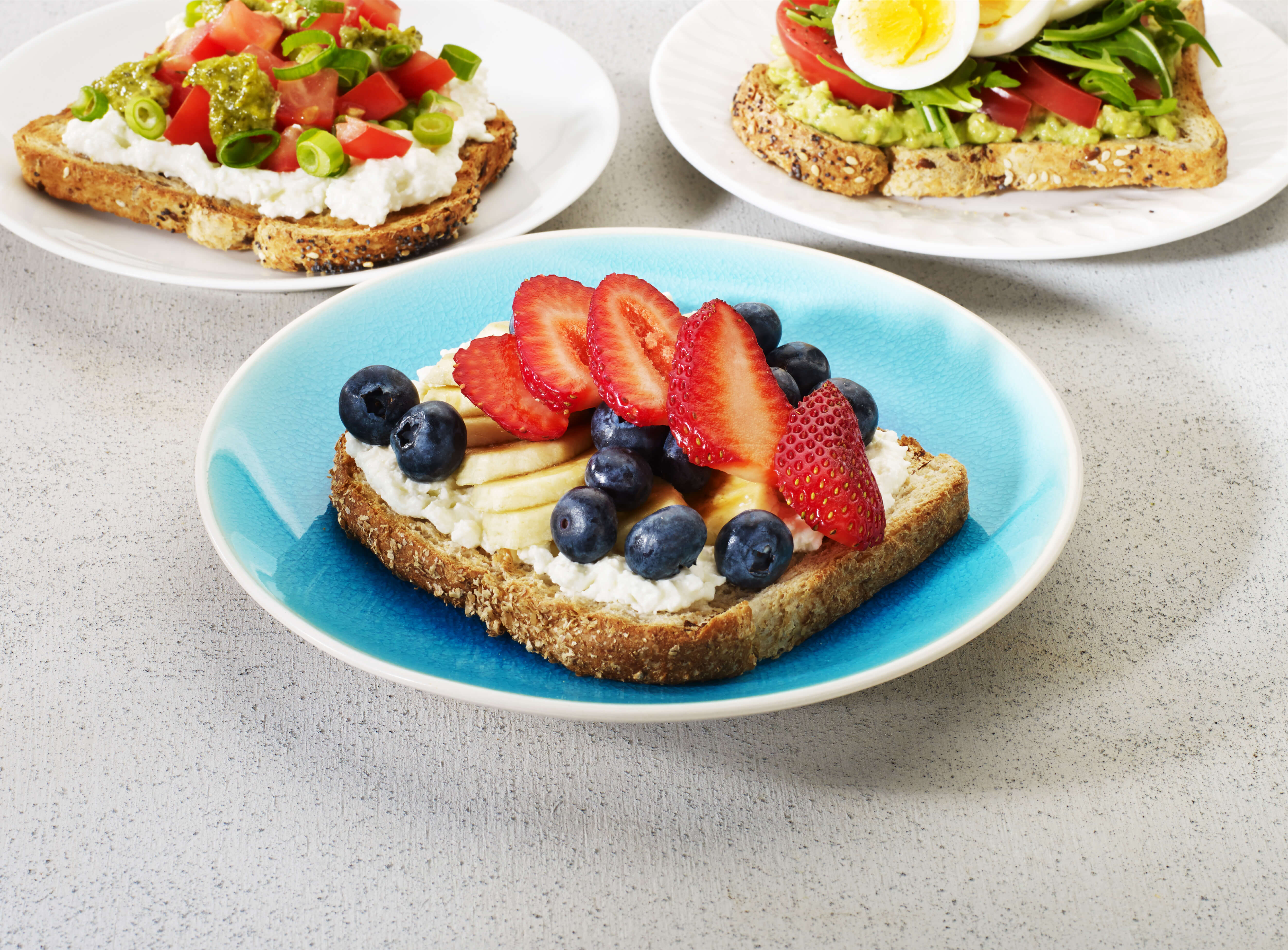 strawberries, banana and blueberries on ricotta on a slice of wholemeal toast 