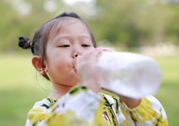 young girl drinking water from a bottle 