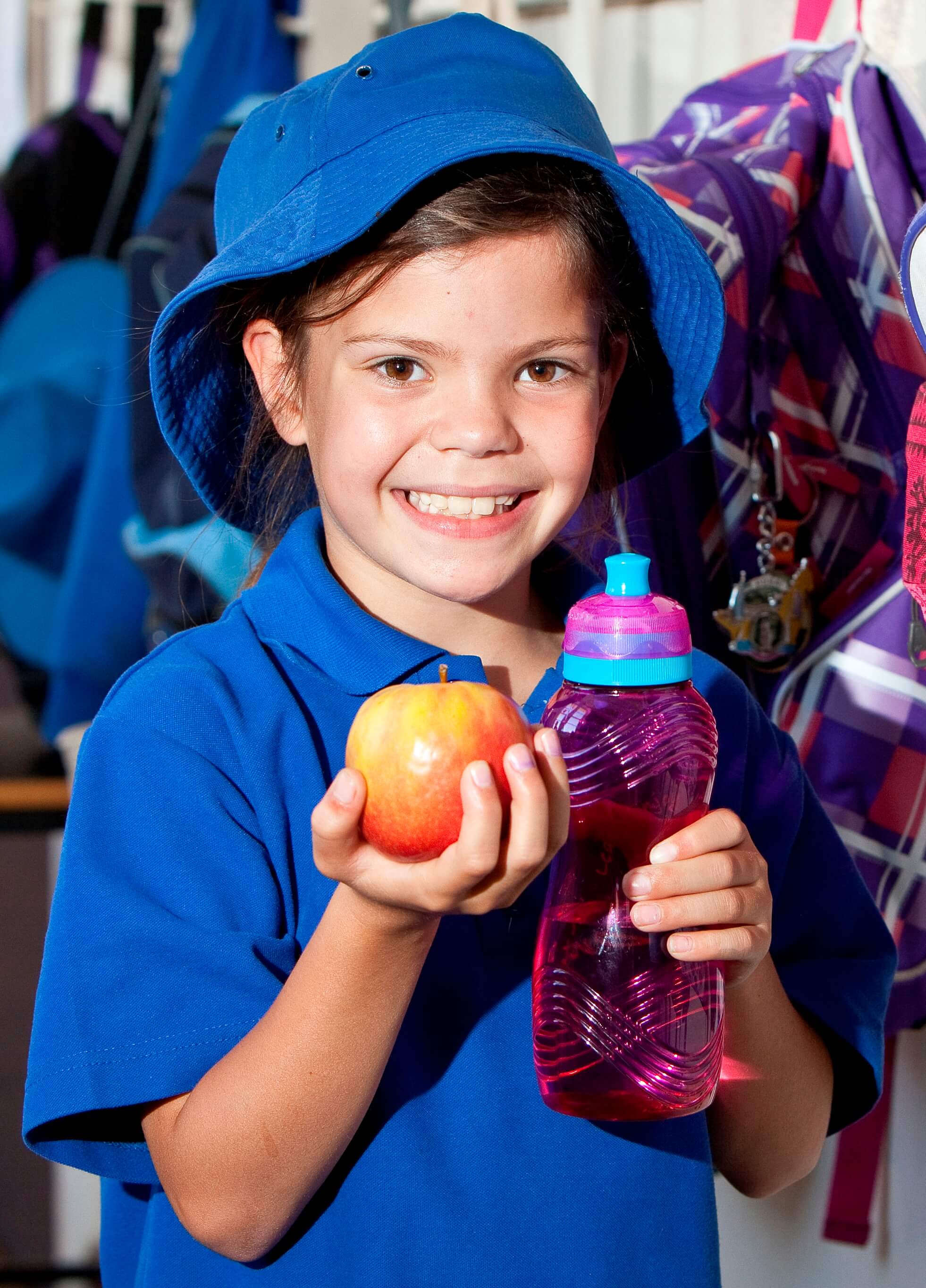 Image of school girl holding and apple and water bottle