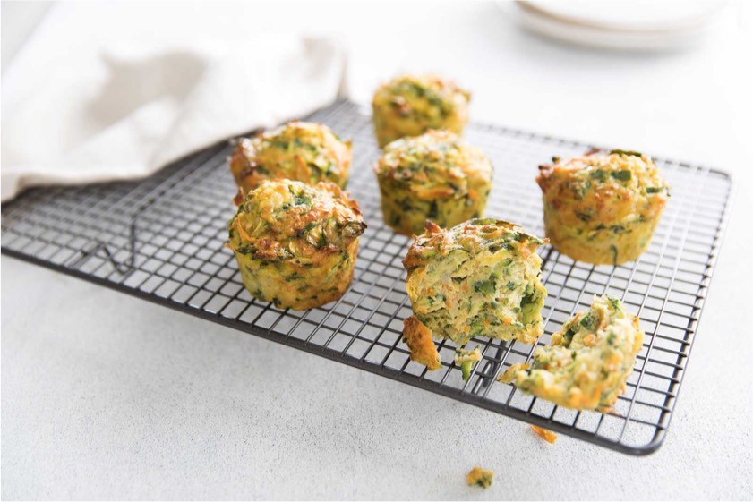 A cooling rack filled with an assortment of muffins, showcasing their golden-brown tops