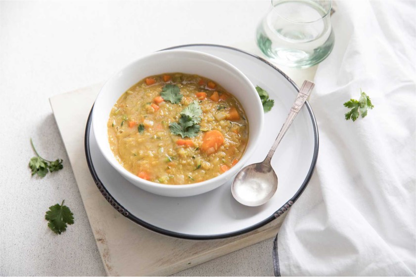 A bowl of lentil soup garnished with fresh carrots and parsley, showcasing a hearty and nutritious meal